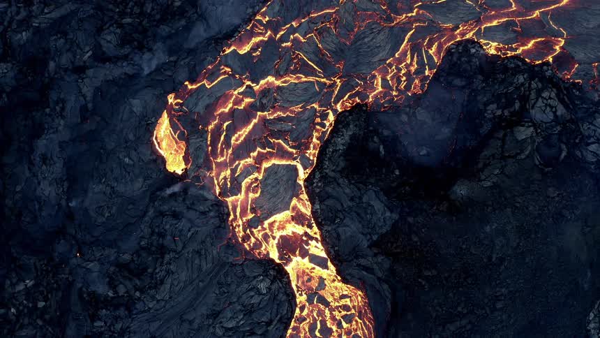 Hot glowing lava flows in the darkness as a volcano erupts