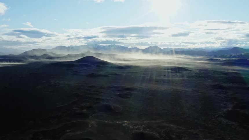 Aerial view of a mountain peak the landscape below and the sun shining through the clouds
