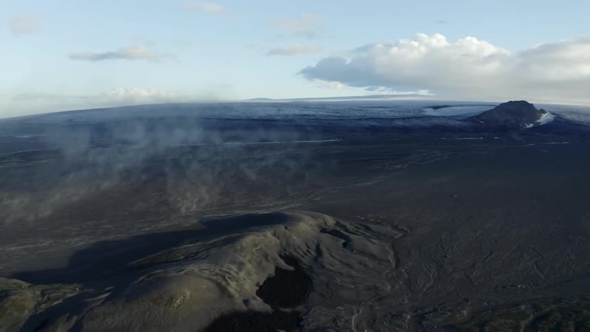 Molten ground near a volcano sitting underneath clouds