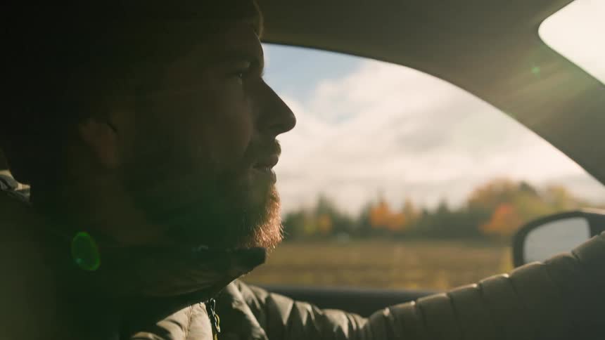 Portrait of a man driving with the sunlight reflecting on his face