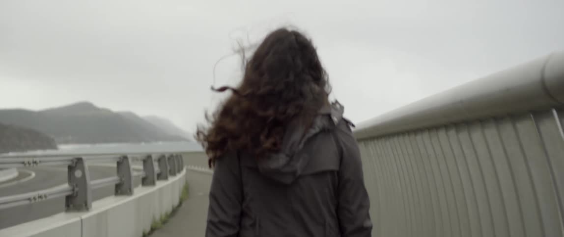 Woman walking down a path on windy and overcast day