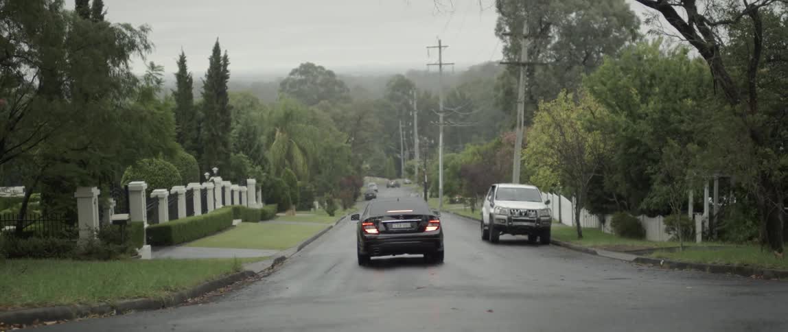 A shiny black car drives down a road