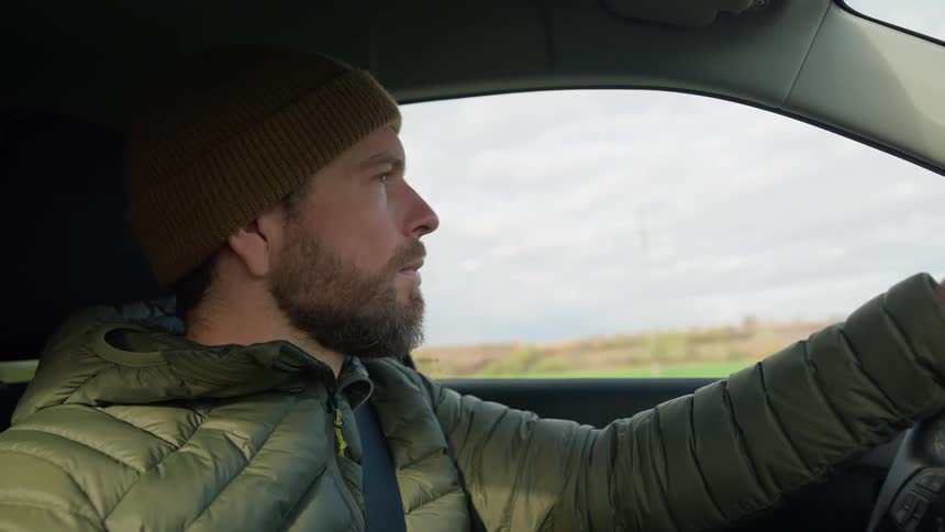 A man looks around as he drives an automobile