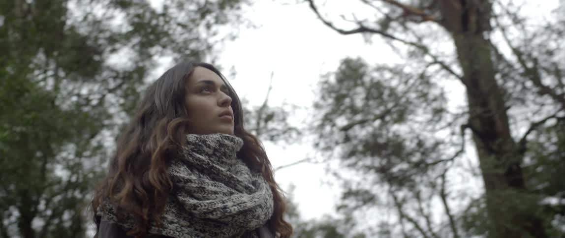 A woman stands before a forest