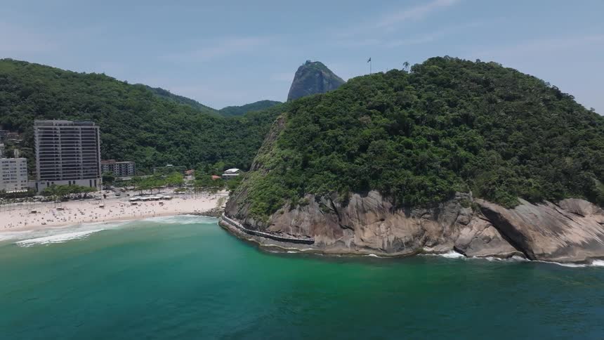 Aerial landscape of a beach with a metropolitan area to one side and the ocean to the other surrounded with hills during day time