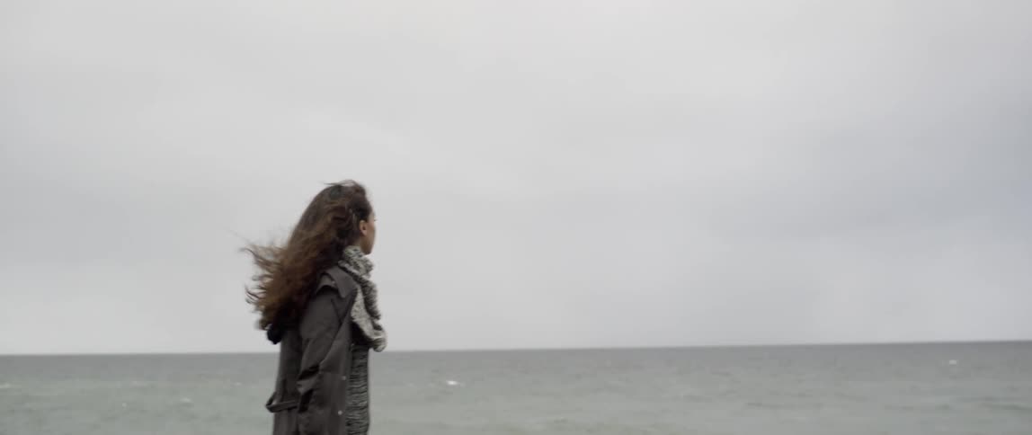 Woman walks on the beach on a windy and cloudy day