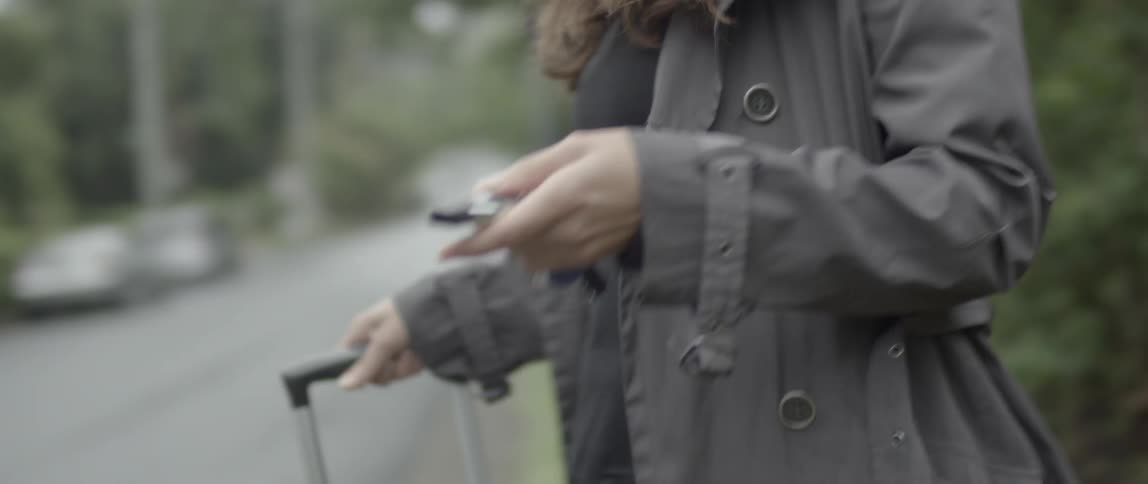 A woman dragging a bag opens her car with the keychain