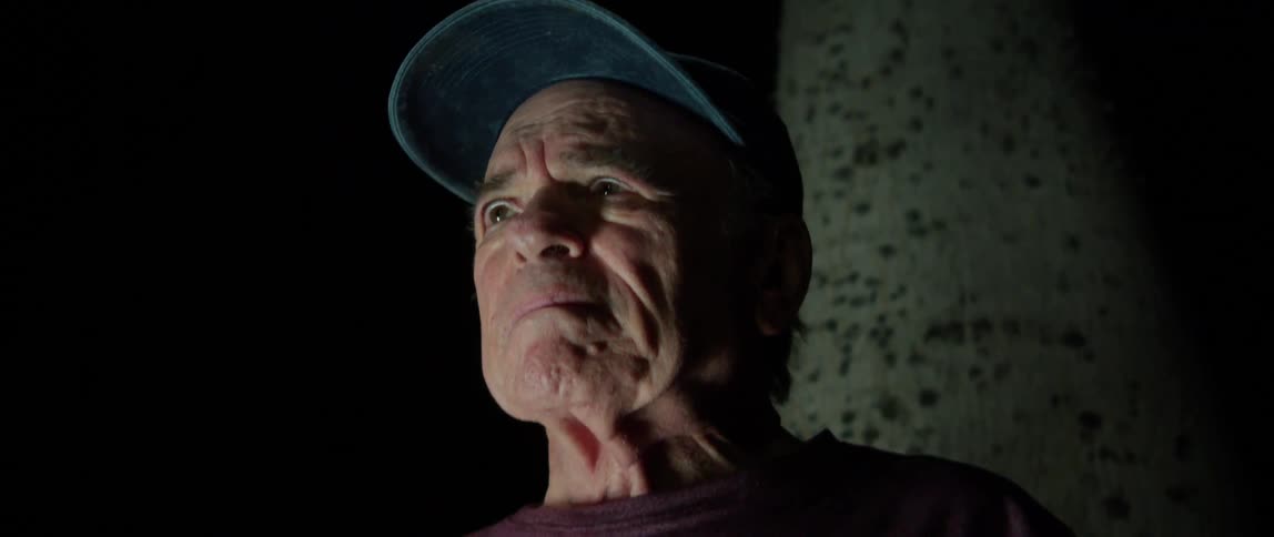 Portrait of an elderly person with a cap in an outdoor setting at night