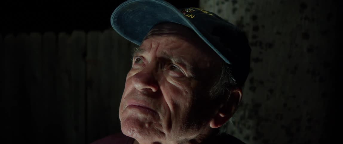 Portrait of an elderly person looking upwards in an outdoor setting at night