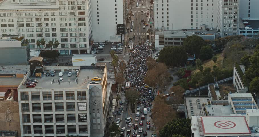 Aerial view of a crowd of people walking in the center of a street surrounded by residential buildings