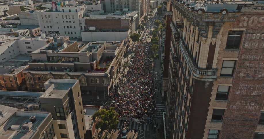 A crowd of people marching on the city street