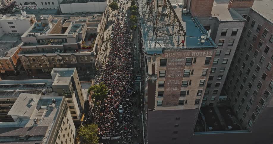 Aerial panorama of a crowd walking on a street surrounded by residential and commercial buildings