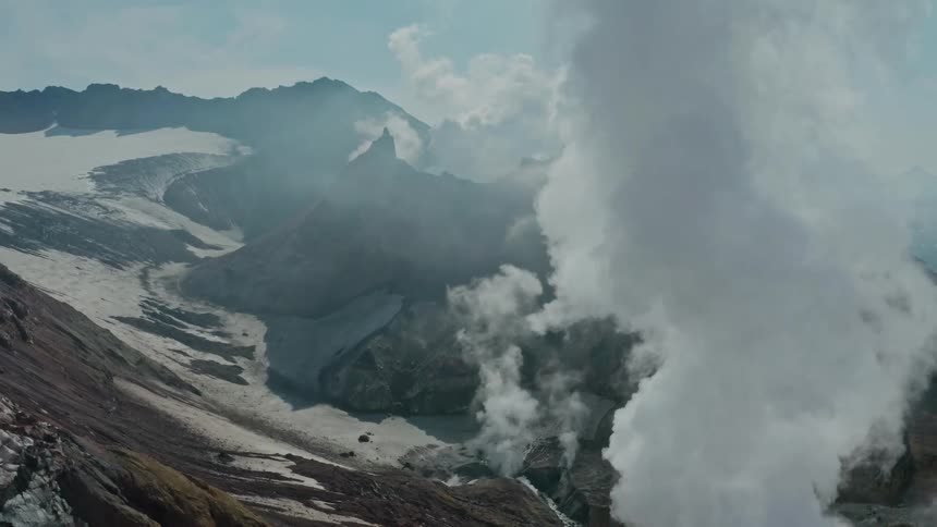 Aerial of a valley with volcanic mountains during an eruption