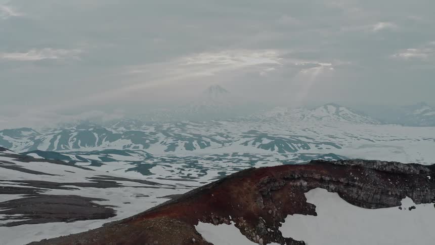 Aerial view of a snow covered mountain range sitting below a grayishblue sky