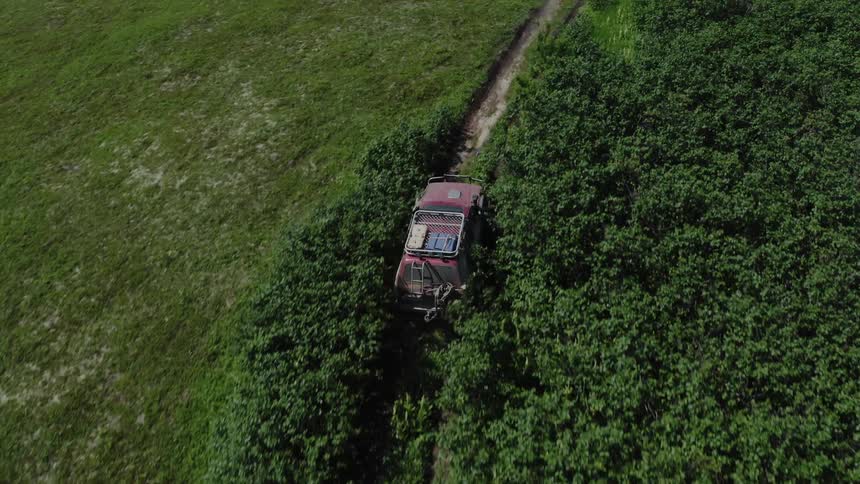 Aerial panorama of a jeep offroading in the midst of nature in a grassland