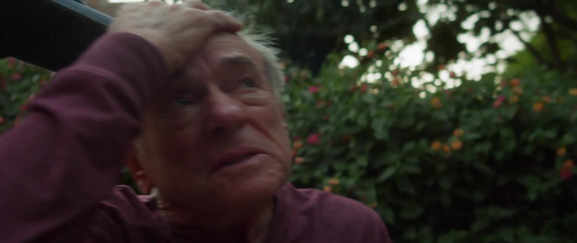 A man removes his hat and rubs his face