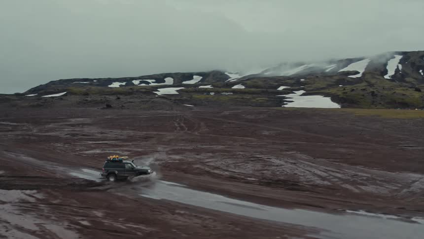 Aerial view of an offroad vehicle in the plains next to the mountains