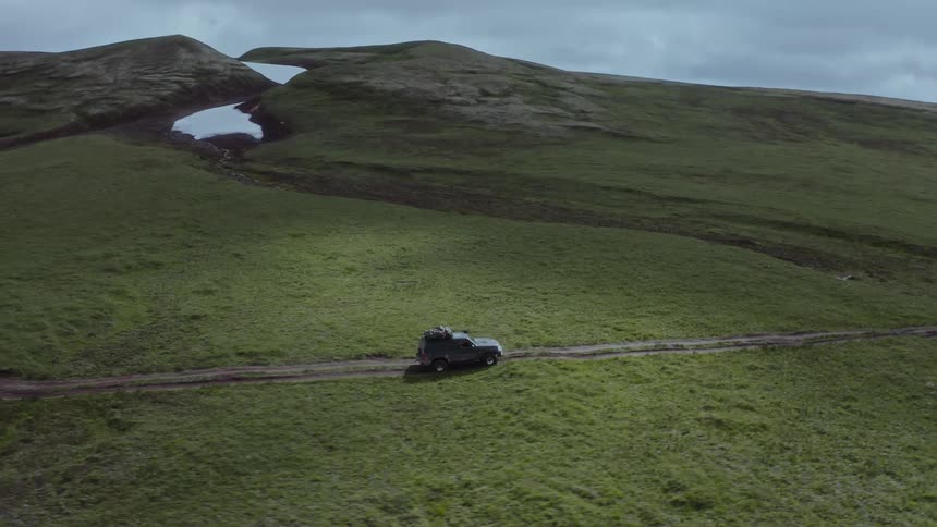 Jeep driving on a dirt road through mountains and rivers