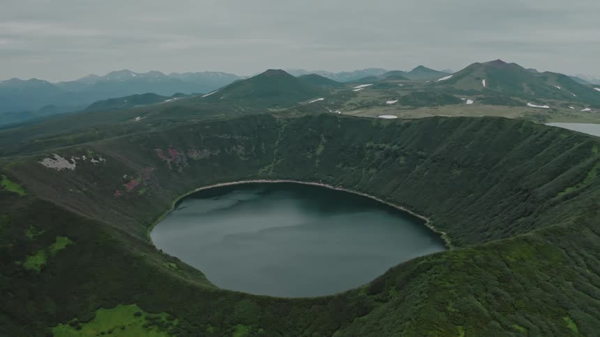 Aerial of a crater lake surrounded by mountains during the day