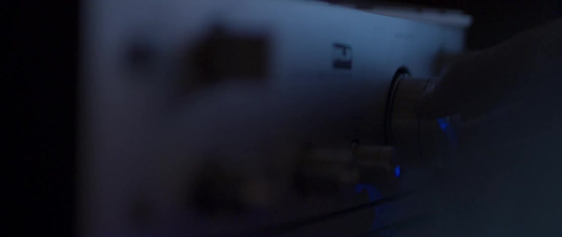 Hand turning the control of an amplifier in a dark room