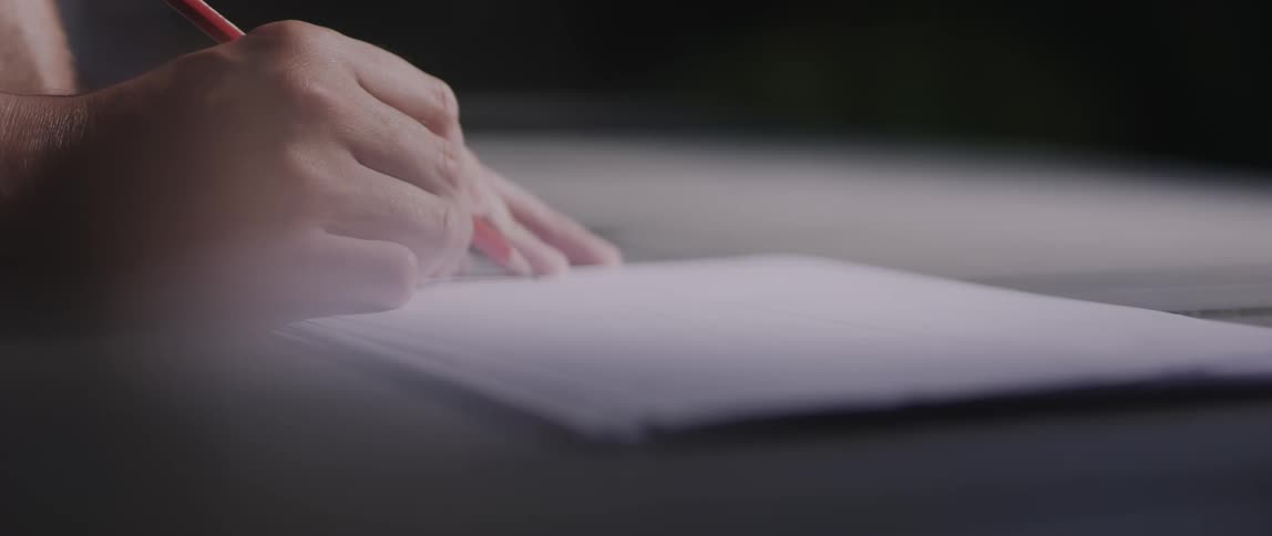 Hands of a person sketching on a white paper with a pencil