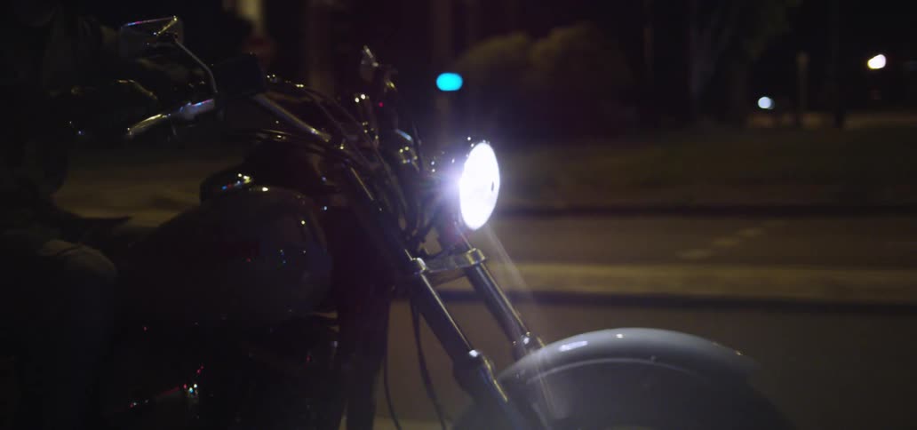 Man riding a motorcycle on a city road at night