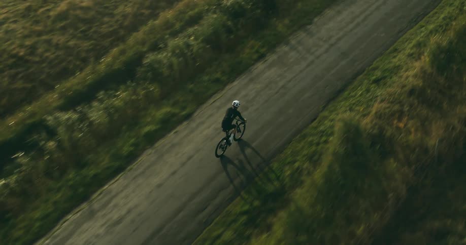 A cyclist pedaling on a road in a rural landscape