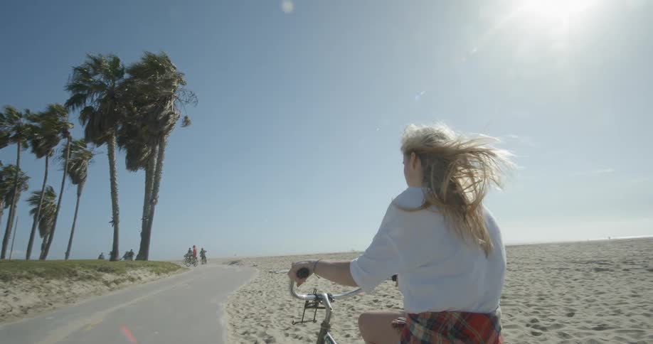 A woman is riding a bicycle on a windy beach