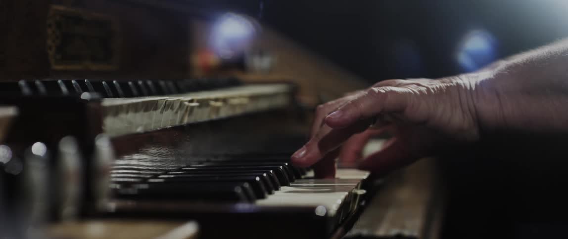 Female pianist sitting under stage lights plays a multi keyboard piano