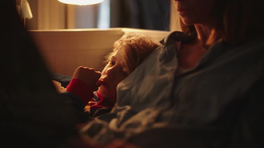 Mother reading a book next to her son on the couch