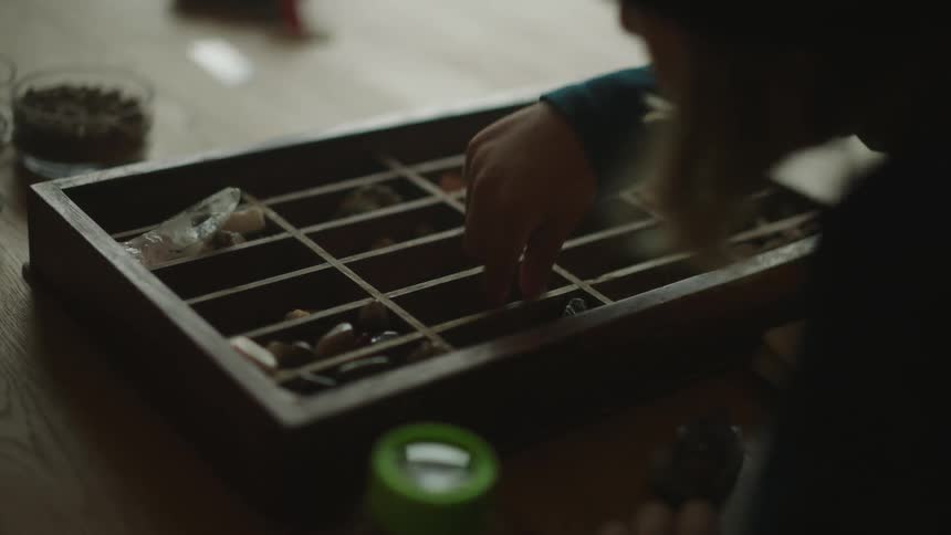 Boy picking up a stone from a box and placing a glass on top