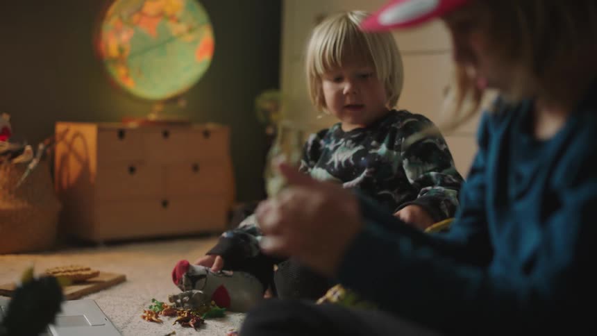 Two children playing with toys while sitting on the floor in a room