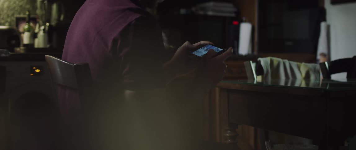 Person sitting in a chair playing on a mobile phone with their hands