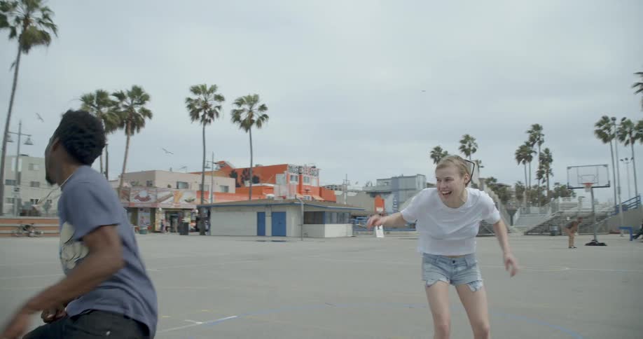 A woman and man play basketball on an outdoor court
