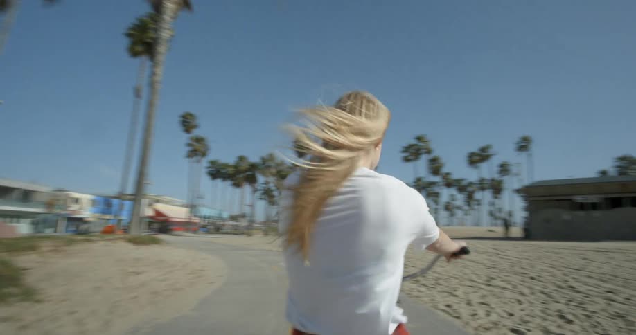 Girl smiling while riding bike near a beach