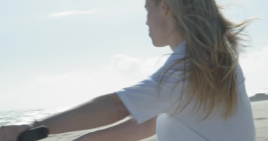 A woman is riding her bike on the beach