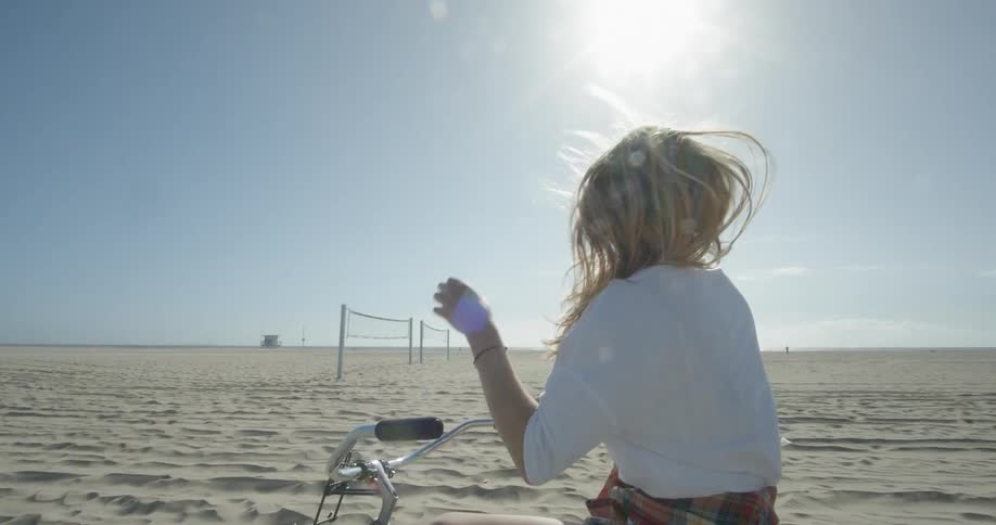 A woman is sitting on her bike by the beach