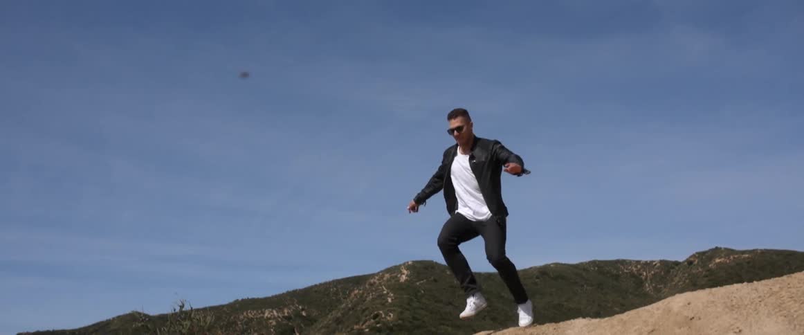 A man runs and jumps down from the top of a hill