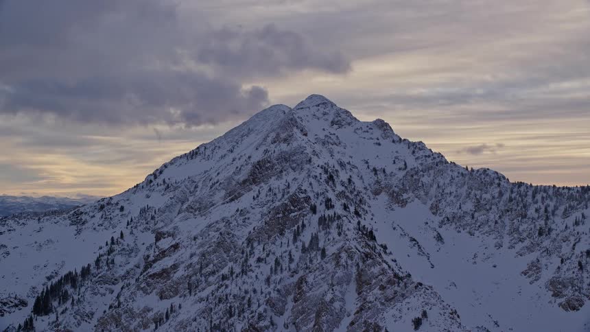 Aerial of craggy snow covered mountains under an overcast sky