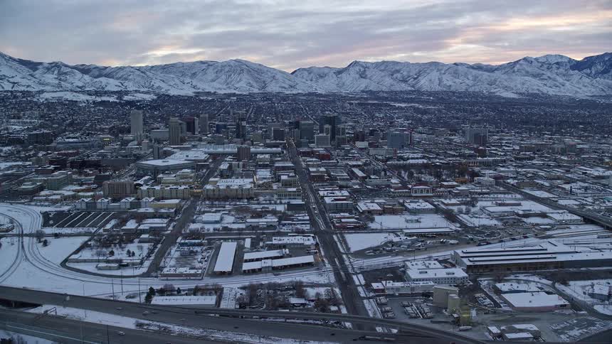 Aerial view of a snowcovered metropolis with mountains on the horizon under a morning sky