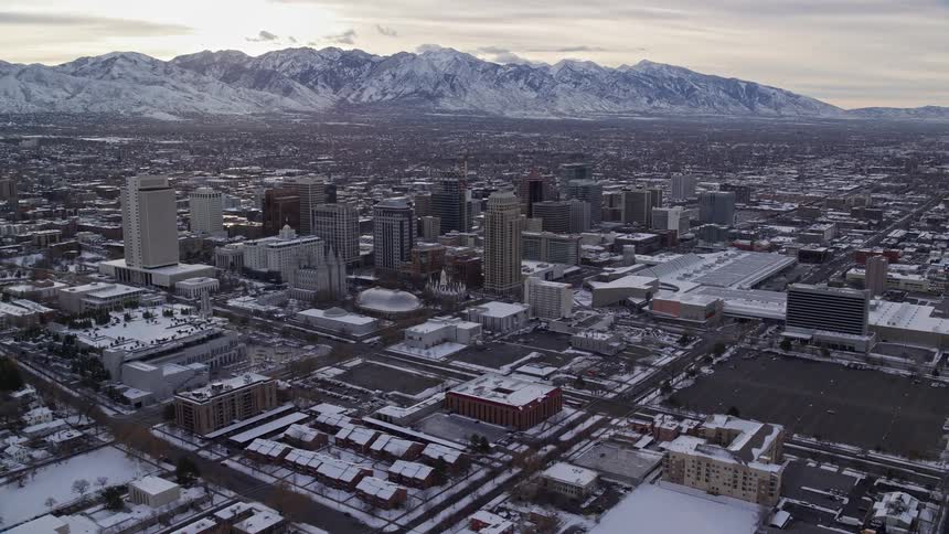 Aerial panorama of a metropolis covered in snow with mountains around it on a morning