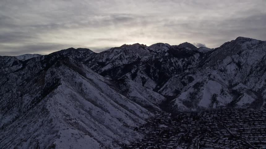 Aerial panorama of a village next to snowcovered mountains under a morning sky