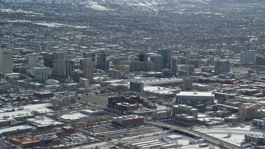 Aerial view of a metropolis covered in snow and surrounded by a chain of mountains