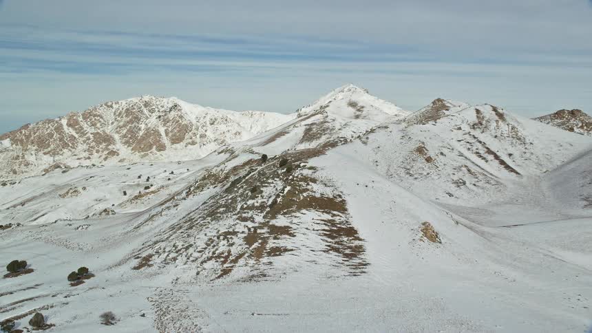 Snow covered mountains with mountains in the distance under a cloudy sky