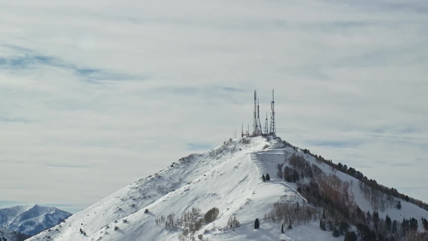 Panorama of mountains with electrical towers on the peaks and covered in snow