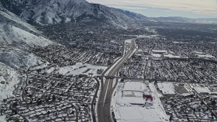 Aerial panorama of an urban city covered in snow with the backdrop of mountains