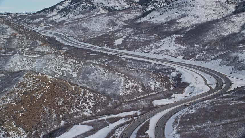 Aerial of moving cars on the road in the middle of mountains at midday
