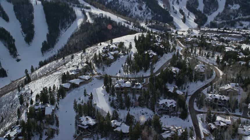 People skiing down a slope in a mountaintop neighborhood