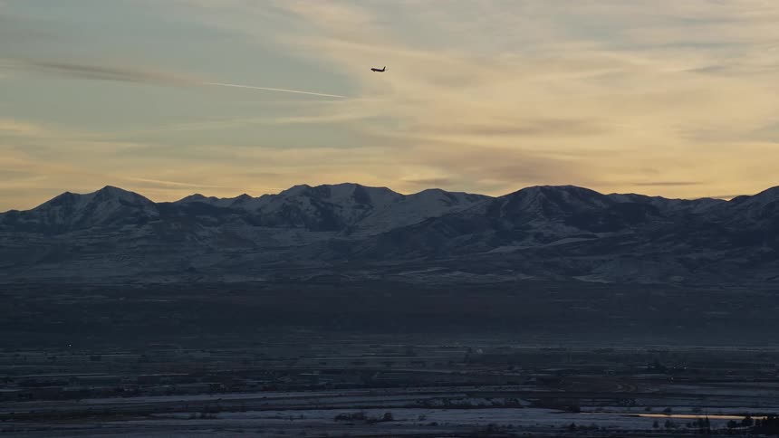 Aerial view of an airplane flying over the mountains at morning