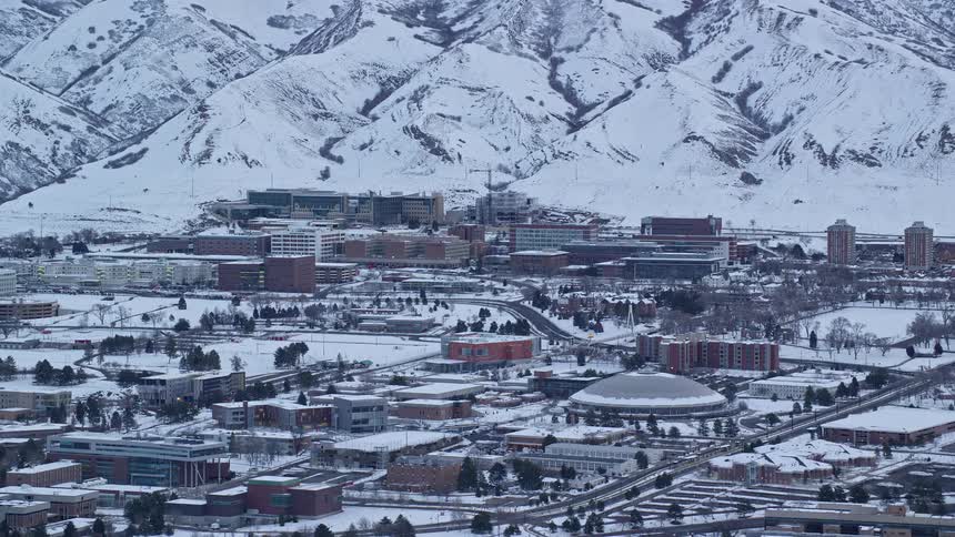 Aerial panorama of an urban city next to a mountain covered in snow
